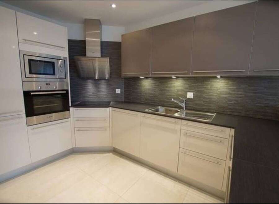 Experience modern living in this sleek kitchen featuring a built-in stainless steel oven and microwave.
