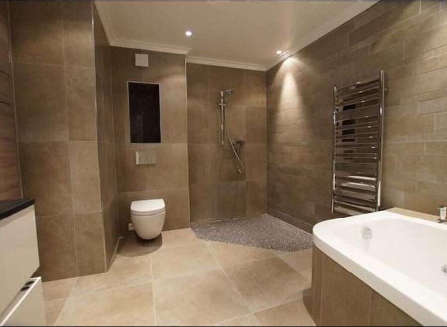 Experience luxury in this modern bathroom featuring a spacious soaking tub and a walk-in shower with pebble flooring.