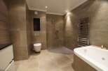 Experience luxury in this modern bathroom featuring a spacious soaking tub and a walk-in shower with pebble flooring.