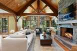 Experience rustic luxury in this stunning living room, featuring a soaring vaulted ceiling with exposed wooden beams and a grand stone fireplace.
