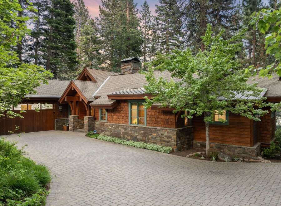 Nestled amidst towering trees, this stunning mountain home boasts a charming exterior with natural wood siding and stone accents.