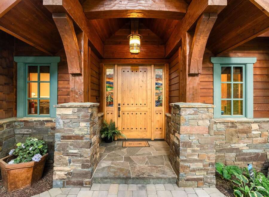 Experience rustic charm with this inviting entryway, featuring a beautiful wooden door with stained glass accents and a welcoming stone facade.