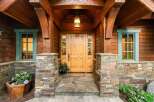 Experience rustic charm with this inviting entryway, featuring a beautiful wooden door with stained glass accents and a welcoming stone facade.