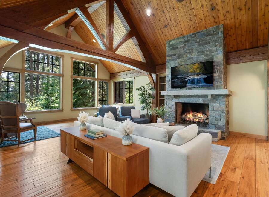 Experience rustic luxury in this stunning living room, featuring a grand stone fireplace and a soaring wood-beamed ceiling.