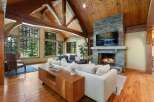 Experience rustic luxury in this stunning living room, featuring a grand stone fireplace and a soaring wood-beamed ceiling.