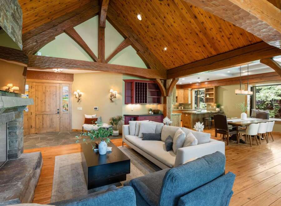 Experience rustic luxury in this stunning mountain home, featuring a grand living area with a stone fireplace and soaring vaulted ceilings with exposed wooden beams.