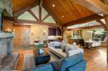 Experience rustic luxury in this stunning mountain home, featuring a grand living area with a stone fireplace and soaring vaulted ceilings with exposed wooden beams.
