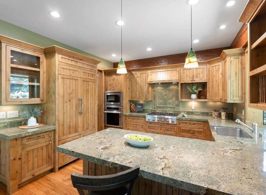 Experience rustic charm in this spacious kitchen featuring custom knotty pine cabinetry and a large granite island perfect for entertaining.