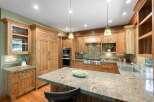 Experience rustic charm in this spacious kitchen featuring custom knotty pine cabinetry and a large granite island perfect for entertaining.