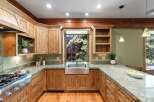 Experience rustic charm in this beautifully appointed kitchen, featuring warm, natural wood cabinetry and a stunning farmhouse sink.