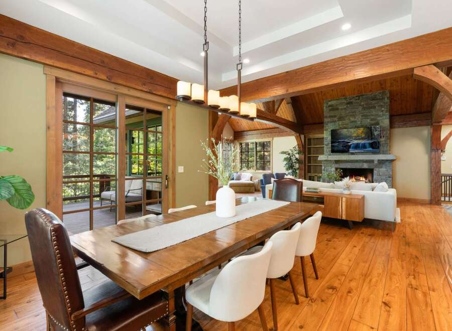 Experience rustic elegance in this spacious dining and living area, featuring a grand wooden dining table and a cozy stone fireplace.