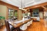 Experience rustic elegance in this spacious dining and living area, featuring a grand wooden dining table and a cozy stone fireplace.