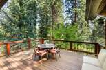 Enjoy the serene mountain lifestyle on this expansive wooden deck, perfect for outdoor dining and relaxation amidst towering trees.