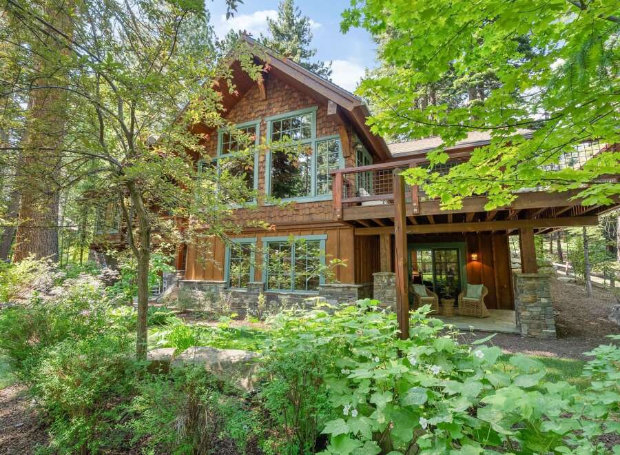 Nestled amidst lush greenery, this stunning mountain home offers a serene retreat with its natural wood siding and stone accents.
