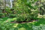 Nestled amidst a lush forest, this property offers a serene retreat with its mature trees and vibrant greenery.