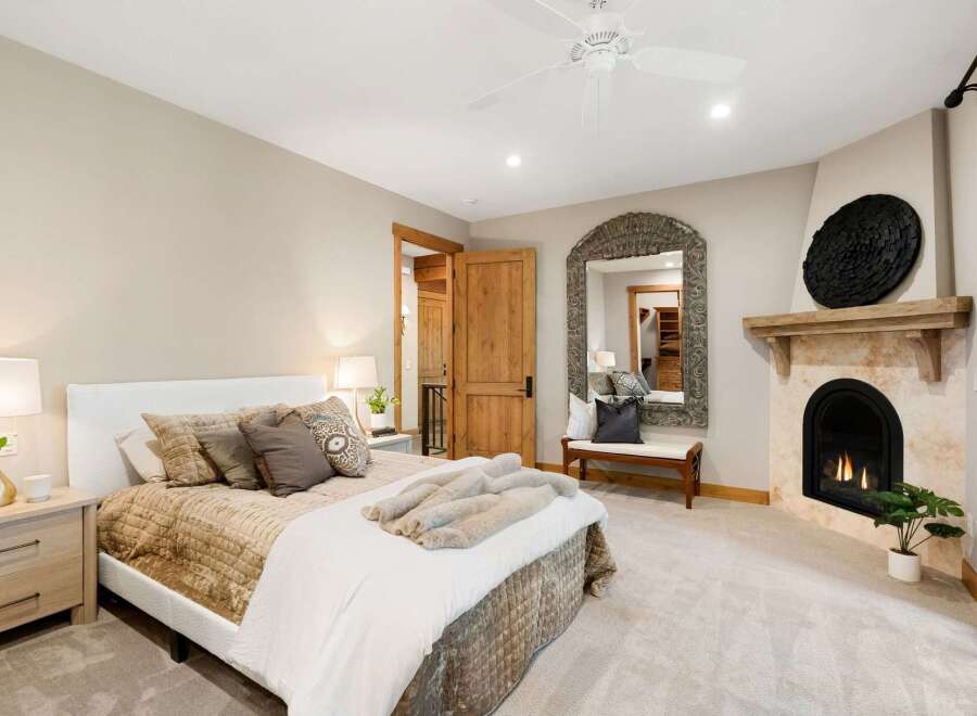 Experience ultimate comfort in this luxurious bedroom, featuring a cozy fireplace and a large ornate mirror.