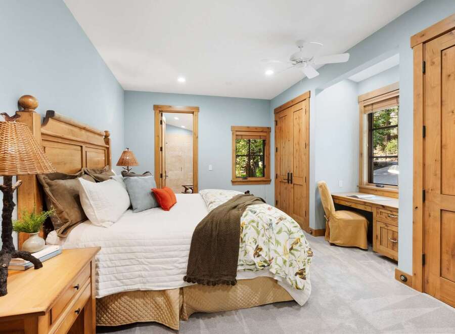 Experience rustic charm in this inviting bedroom, featuring a cozy queen-size bed with a natural wood headboard and a charming nature-inspired duvet.