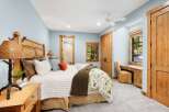 Experience rustic charm in this inviting bedroom, featuring a cozy queen-size bed with a natural wood headboard and a charming nature-inspired duvet.