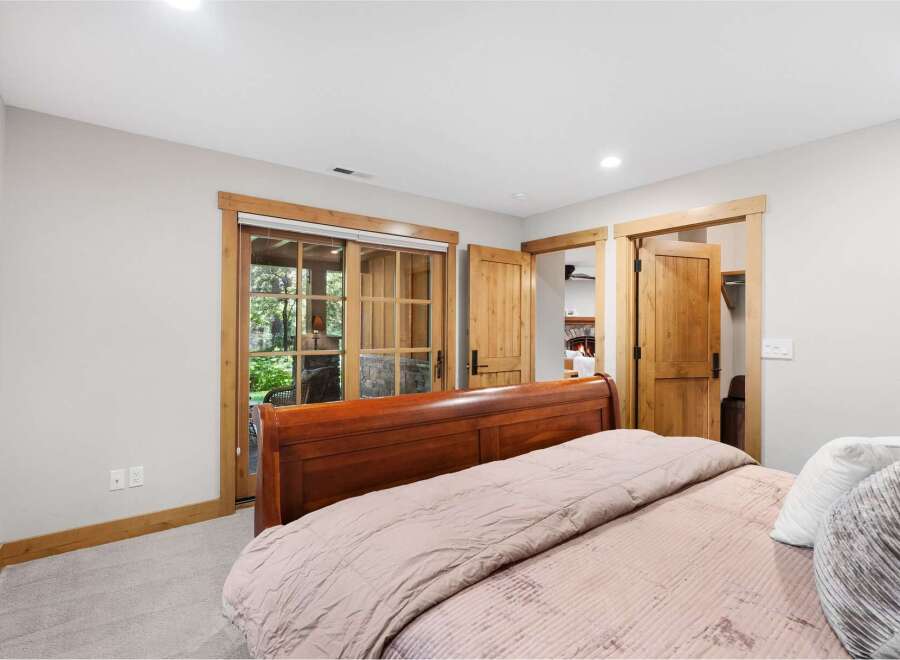 Experience rustic charm in this inviting bedroom featuring a warm wooden sleigh bed and direct access to the outdoors through elegant glass doors.