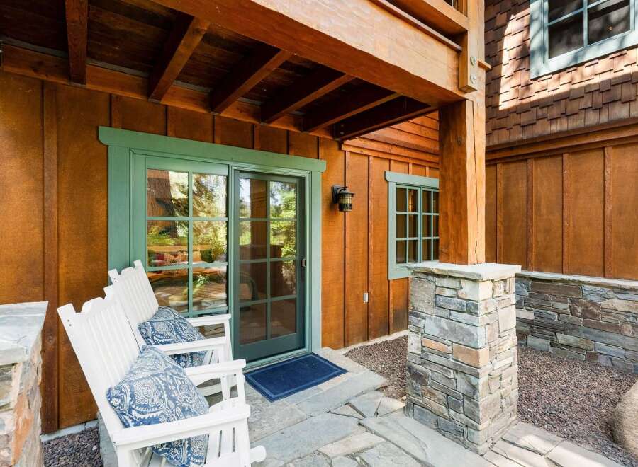 Enjoy the serene outdoors from this charming patio featuring two white Adirondack chairs with decorative blue cushions.