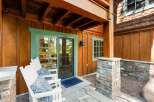 Enjoy the serene outdoors from this charming patio featuring two white Adirondack chairs with decorative blue cushions.