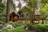 Nestled amidst towering trees, this stunning wooden lodge offers a serene retreat with a charming water feature and lush landscaping.