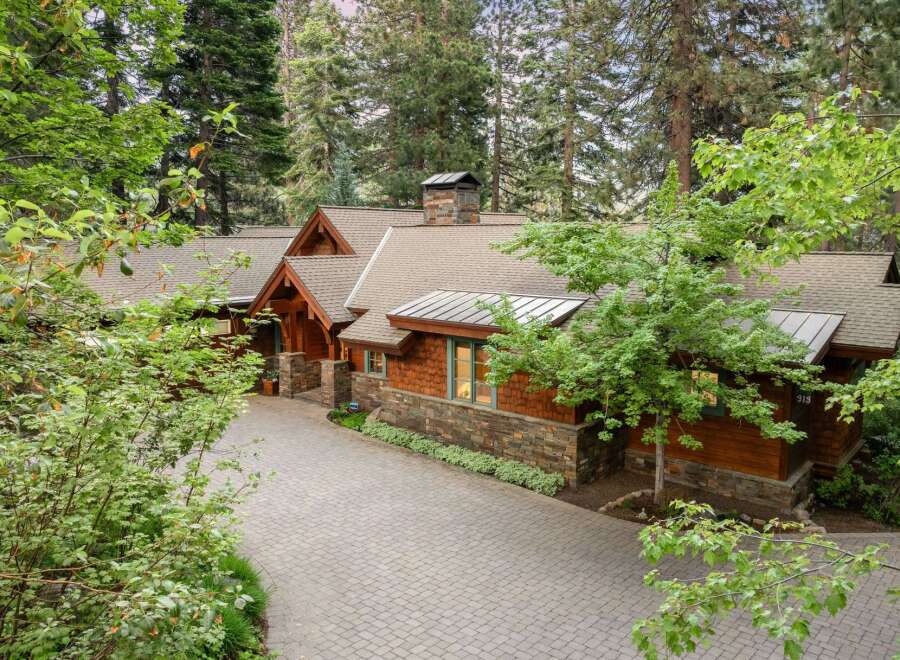 Nestled amidst towering trees, this stunning mountain home boasts a charming exterior with natural wood siding and stone accents.