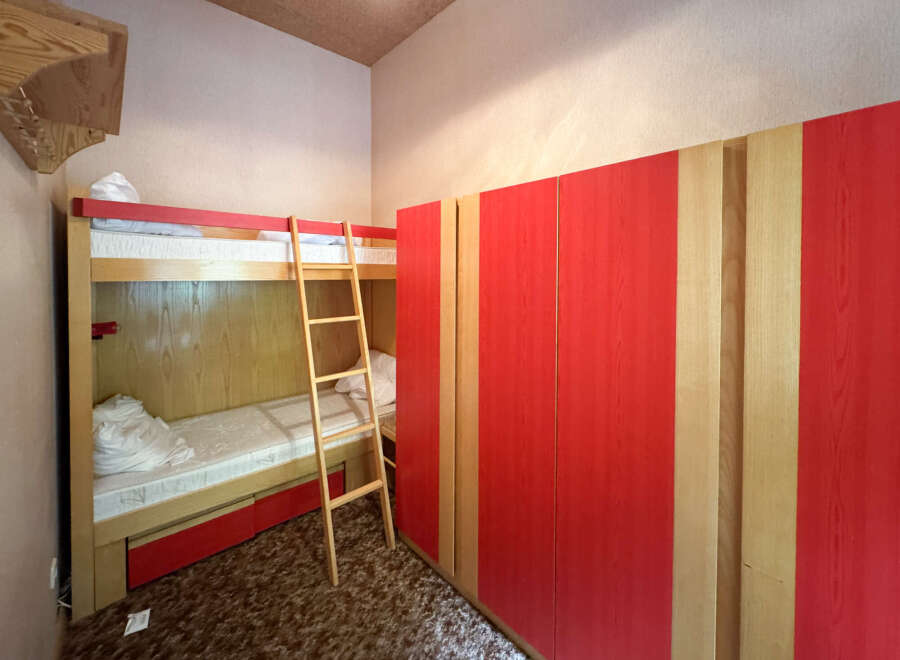 Discover this charming bedroom featuring a space-saving bunk bed with a convenient ladder, perfect for maximizing room utility.