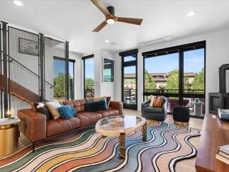 Experience modern living in this stunning open-concept living area, featuring a luxurious brown leather sofa and a unique, eye-catching wavy rug.