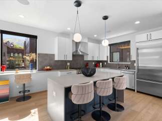 Experience modern luxury in this stunning kitchen, featuring sleek white cabinetry and a spacious island perfect for entertaining.