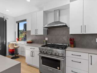 Experience modern living in this sleek kitchen featuring stainless steel appliances, including a professional-grade gas range and a powerful range hood.