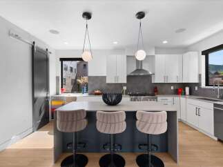 Experience modern living in this stunning kitchen featuring a sleek island with plush bar stools, perfect for casual dining or entertaining.