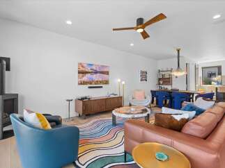 Experience modern living in this vibrant open-concept space, featuring a stylish living area with a contemporary fireplace and a colorful abstract rug.