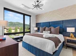 Experience luxury mountain living in this stunning bedroom featuring a king-sized bed with a plush blue upholstered headboard and a cozy brown throw.