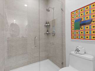 Experience modern luxury in this stunning bathroom featuring a sleek glass-enclosed shower with textured tile walls and a rainfall showerhead.