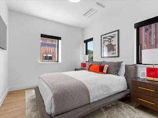 Experience modern comfort in this stylish bedroom, featuring a plush bed adorned with decorative pillows and a cozy throw.