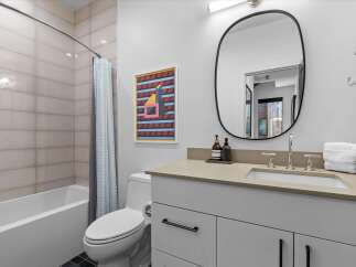 This modern bathroom features a sleek white vanity with a stone countertop, complemented by a large oval mirror and contemporary fixtures.