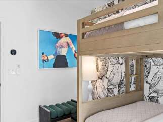 This charming bedroom features a stylish bunk bed with playful owl-themed wallpaper, perfect for a kids' room or guest space.