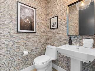 This stylish powder room features unique, text-patterned wallpaper that adds a touch of personality and intrigue.