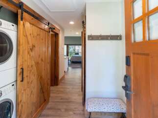 Step into this charming entryway featuring a convenient stacked washer and dryer hidden behind a rustic barn door.
