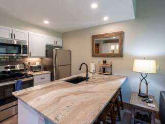 Discover this charming kitchen featuring sleek stainless steel appliances, including a microwave and refrigerator, complemented by modern white cabinetry.