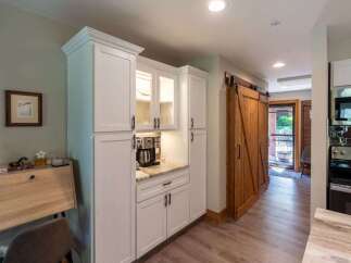 Discover a charming kitchen area featuring a built-in coffee station with a sleek coffee maker and ample cabinet storage.