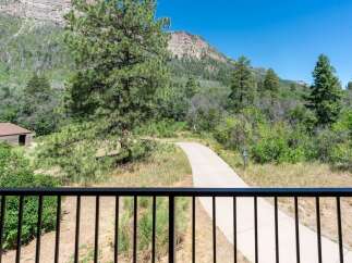 Enjoy the serene mountain views from this property, featuring a paved walking path leading through lush greenery and mature trees.