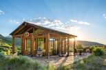 Experience breathtaking sunset views from this modern cabin, featuring expansive glass walls and a covered porch perfect for outdoor living.