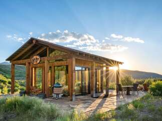 Experience breathtaking sunset views from this modern cabin, featuring expansive glass walls and a covered porch perfect for outdoor living.