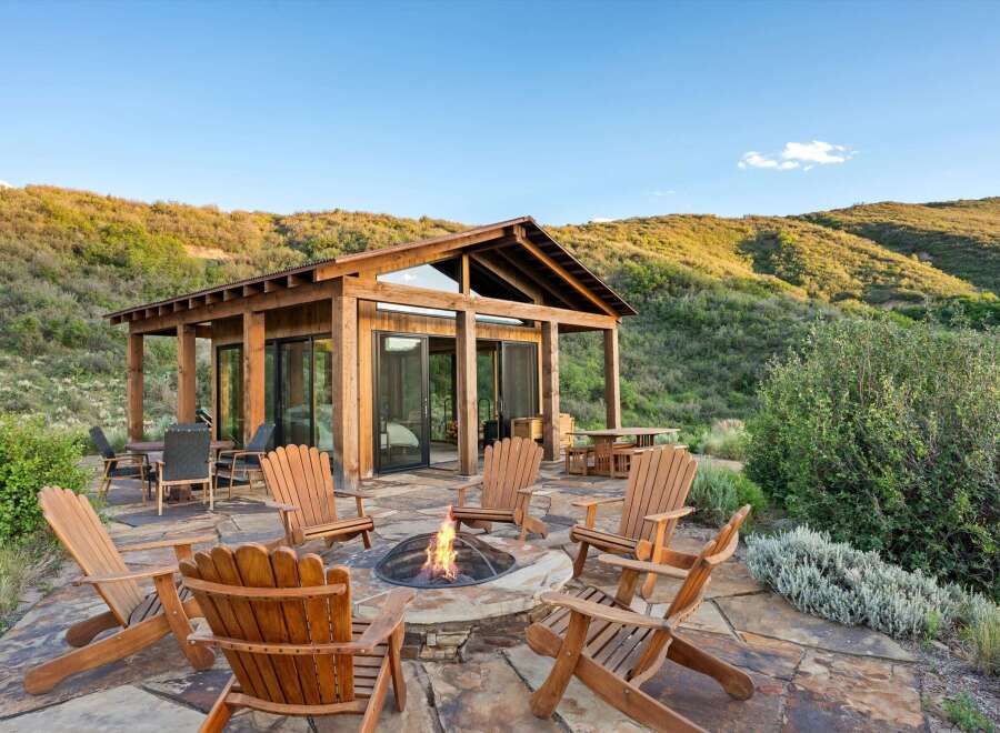 Experience the ultimate outdoor living with this stunning patio featuring a cozy fire pit surrounded by comfortable Adirondack chairs.