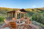 Experience the ultimate outdoor living with this stunning patio featuring a cozy fire pit surrounded by comfortable Adirondack chairs.