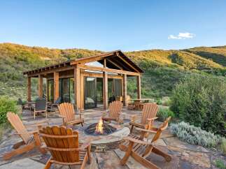 Experience the ultimate outdoor living with this stunning patio featuring a cozy fire pit surrounded by comfortable Adirondack chairs.