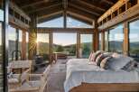 Experience breathtaking sunset views from this stunning bedroom, featuring expansive floor-to-ceiling windows that seamlessly blend indoor and outdoor living.