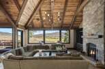 Experience luxurious mountain living in this stunning great room, featuring a massive stone fireplace and a vaulted wood-beamed ceiling.